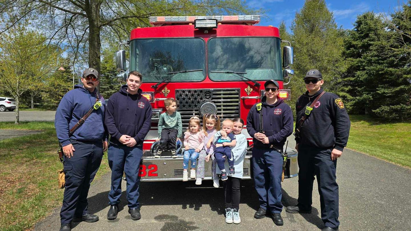 Career firefighters meeting local children beside a fire engine