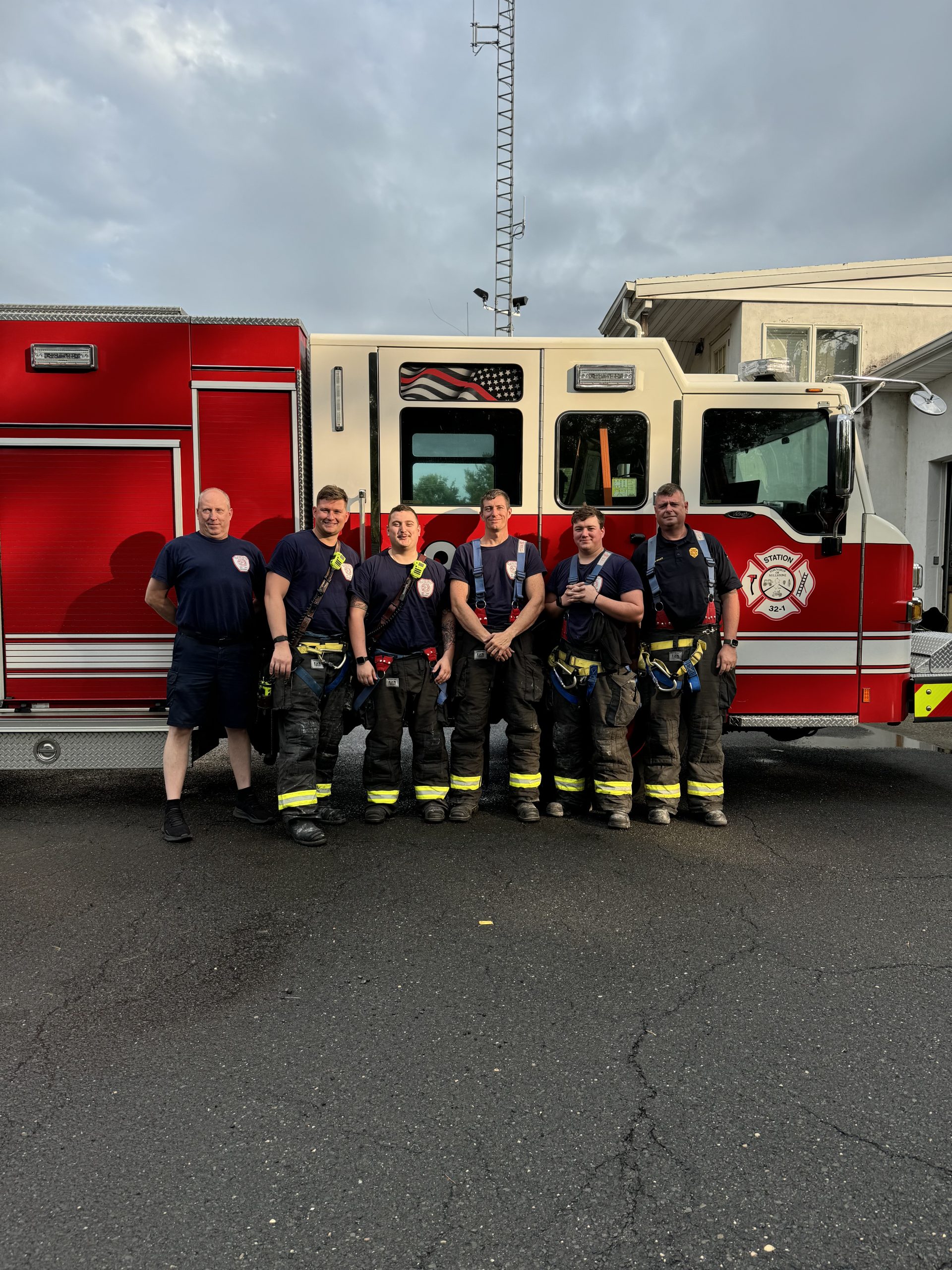 Six firefighters standing together in front of Station 32-1 fire apparatus.