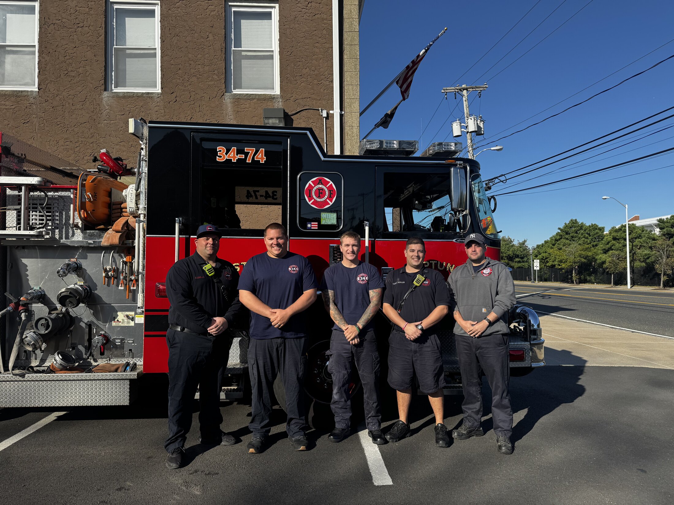 Neptune Township firefighters standing together in front of an IAFF-marked fire engine