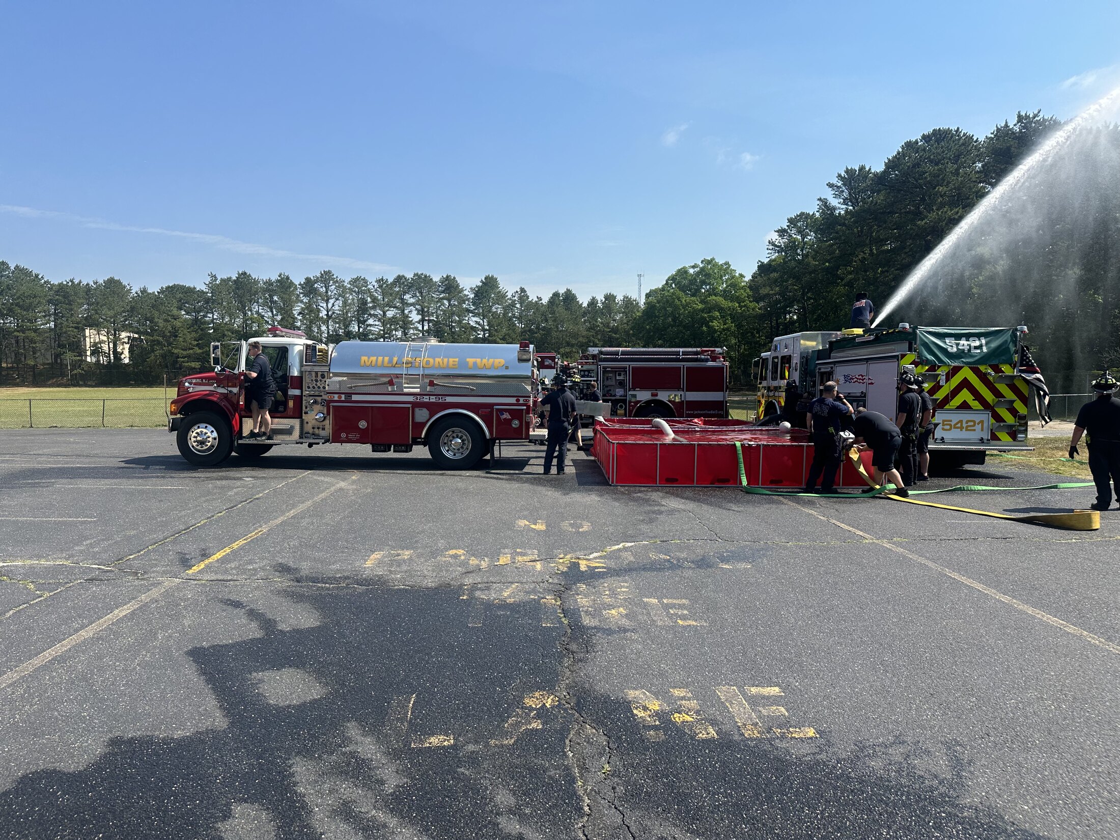 Firefighters training with apparatus while a master stream operates