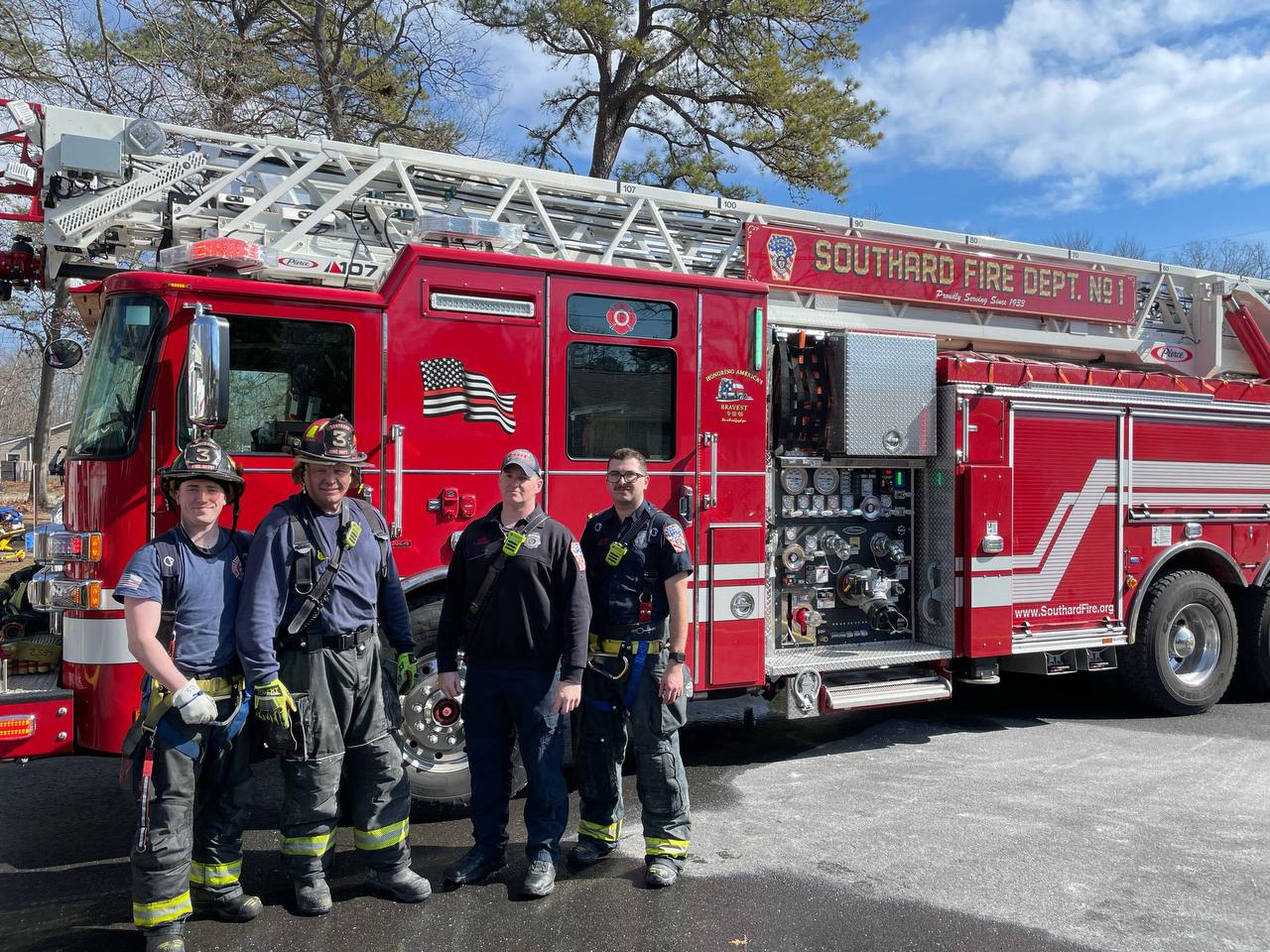 Four firefighters standing in front of Southard Fire Department ladder apparatus.
